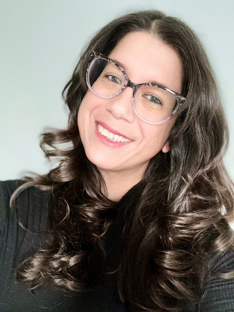 Portrait of Stephanie with brown hair and sparkle glasses in a black turtleneck